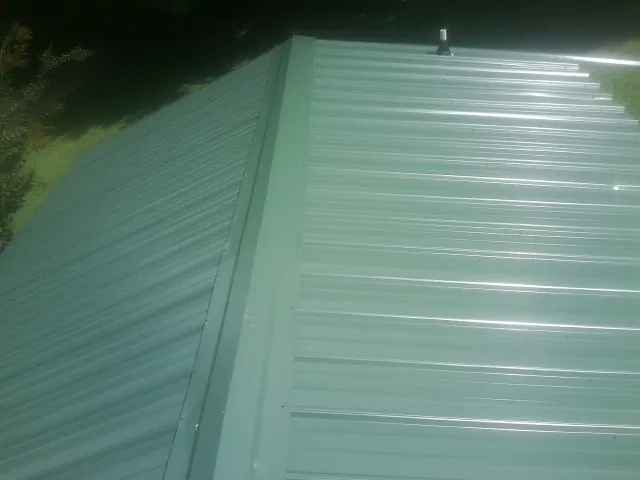 New green metal panels meeting at the ridge of a roof — Flat Roof Repair work by our crew in Pavo