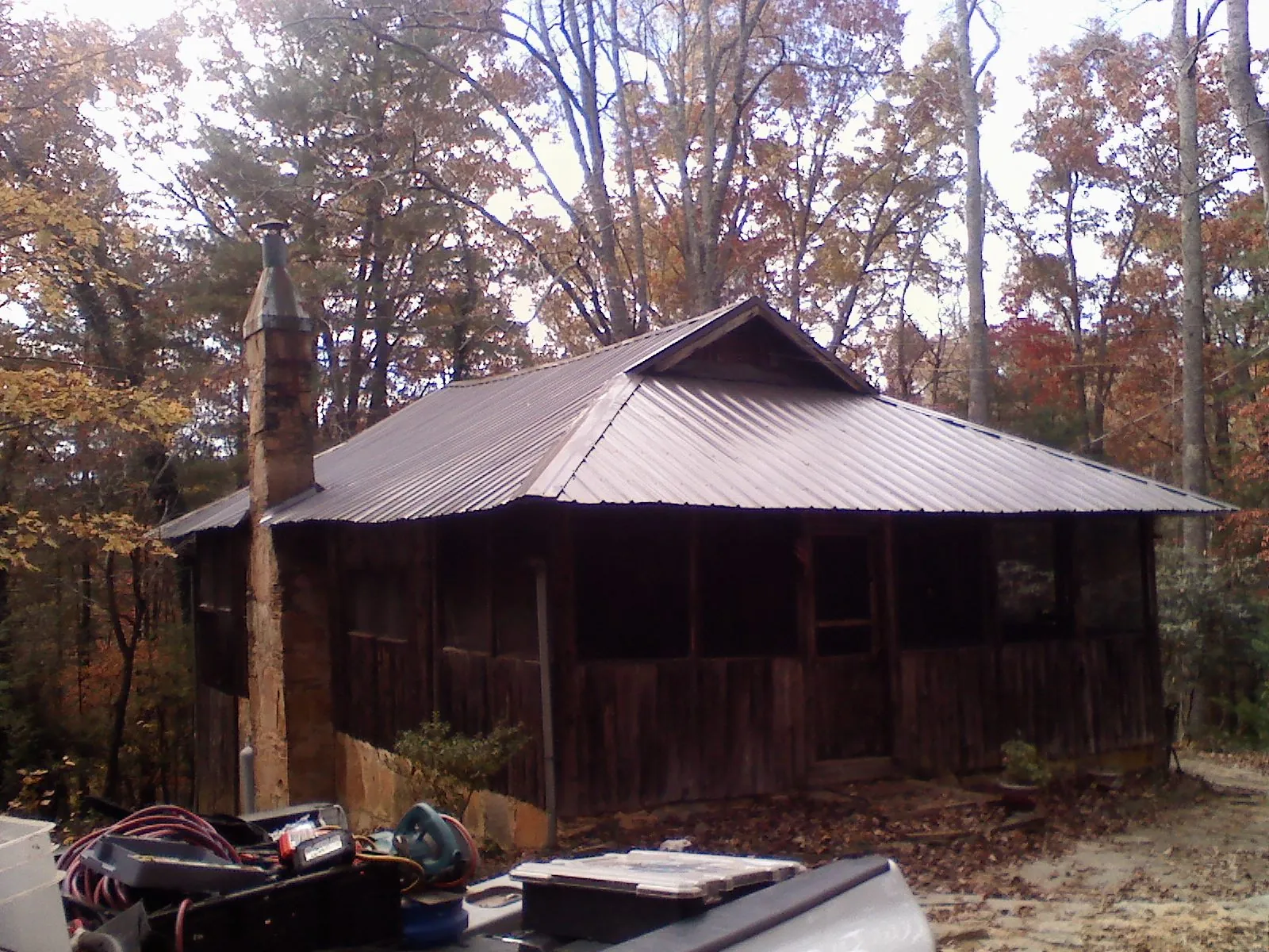 Brown metal hip roof on an old cabin with a stone chimney in Pavo