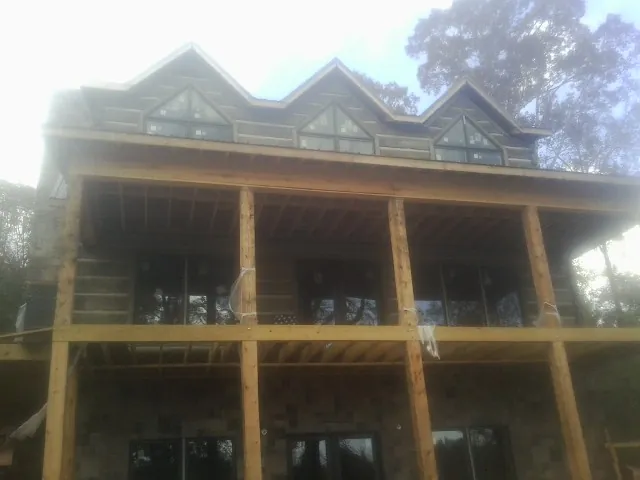 Dormers and porch framing on a large log home under construction — Roof Coating work by our crew in Pavo