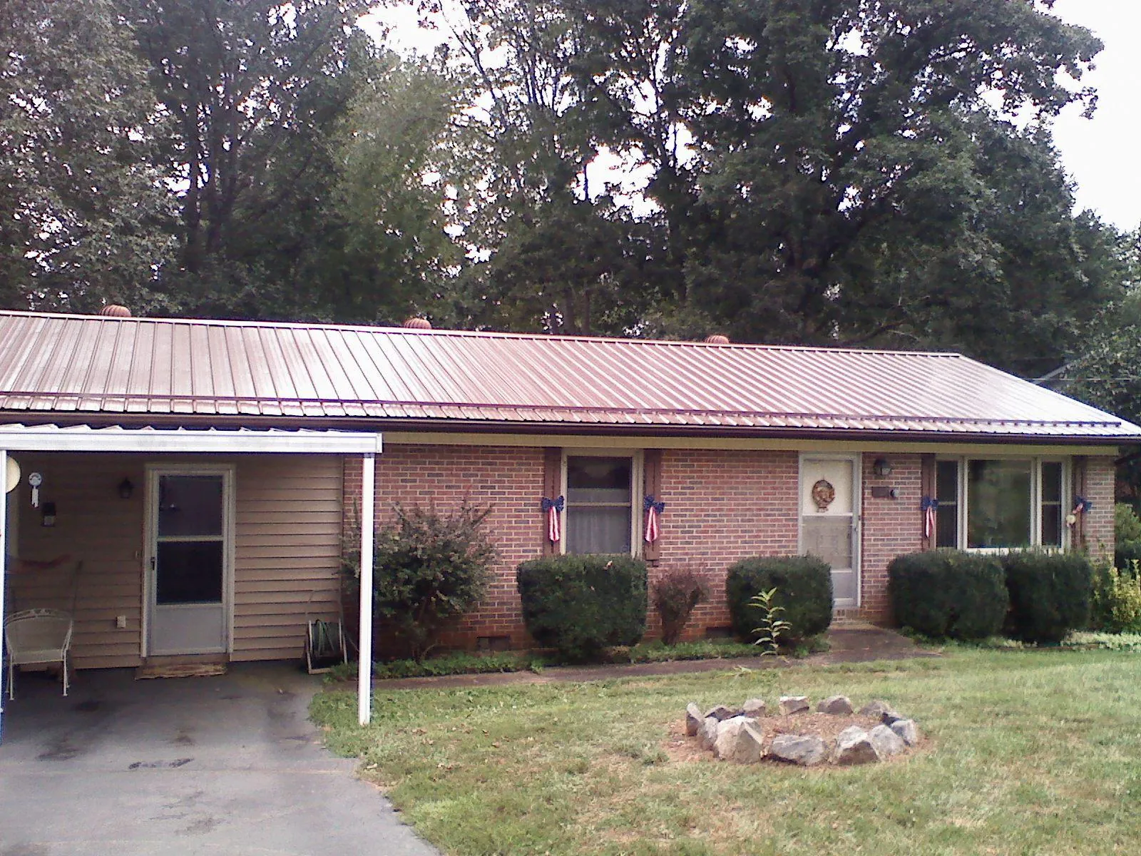 Bronze metal roof and carport on a brick ranch home — Roof Repair work by our crew in Pavo