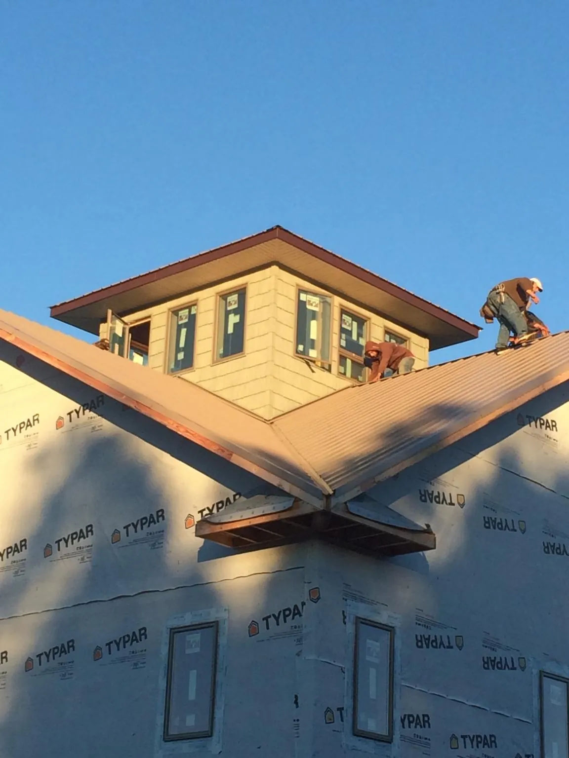 Roofers working around a rooftop cupola on a new metal roof at sunset — Roof Waterproofing in Pavo by Roofing Brothers